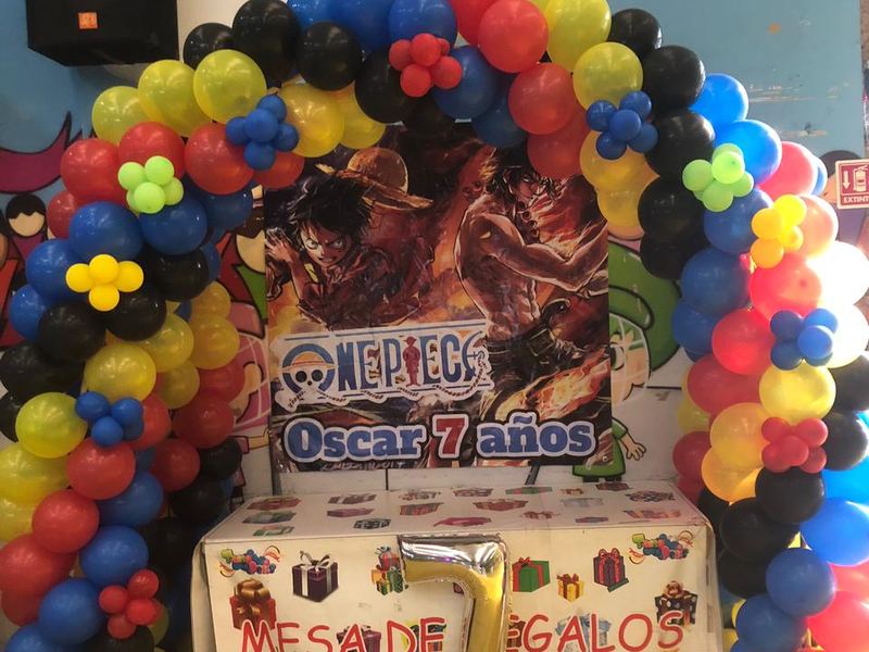 Mesa de regalos con arco de globos rojo, azul, negro y amarillo para una fiesta temática